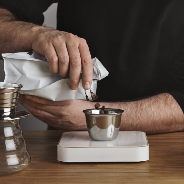 Male barista in pours roasted coffee beans